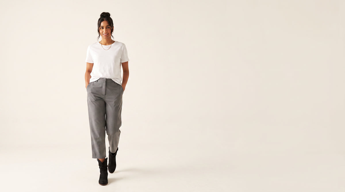 Woman in a white tee and grey cropped trousers walking in black suede slouchy western ankle boots
