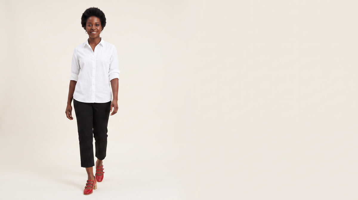 Woman in a white shirt and cropped black trousers walking in wine red triple strap block heel pumps